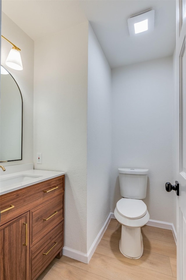 bathroom with toilet, vanity, and hardwood / wood-style floors