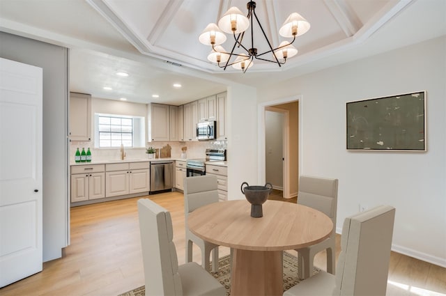 dining space featuring sink, light wood-type flooring, and a notable chandelier