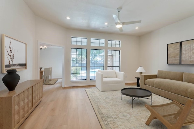 living room featuring light hardwood / wood-style flooring and ceiling fan with notable chandelier