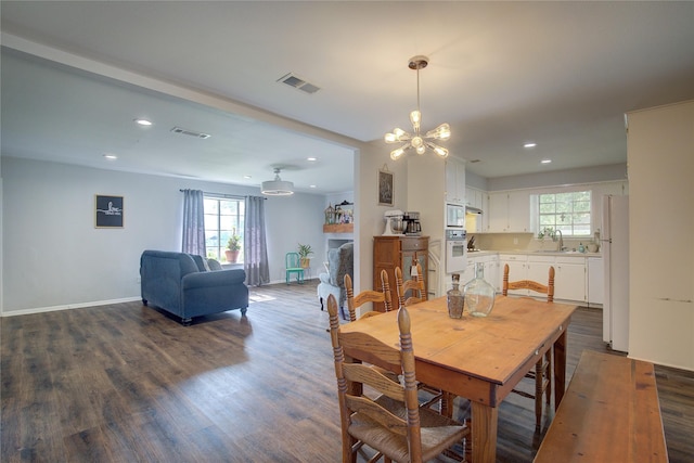 dining space with dark wood-type flooring, sink, and a chandelier