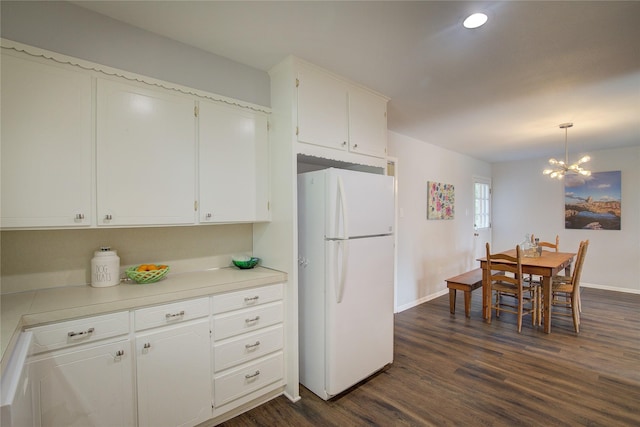 kitchen featuring decorative light fixtures, white cabinetry, dark hardwood / wood-style flooring, white fridge, and a chandelier