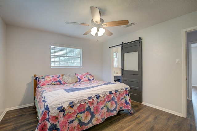 bedroom with dark wood-type flooring, ceiling fan, and a barn door