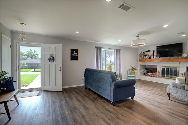 living room with dark wood-type flooring, a brick fireplace, and ornamental molding