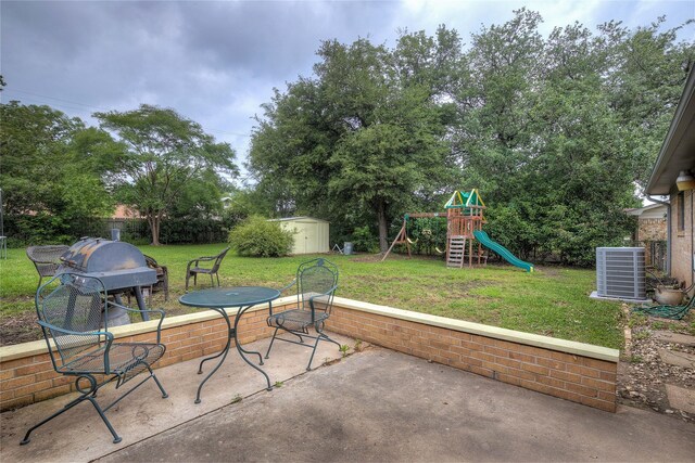 view of patio featuring a playground, cooling unit, area for grilling, and a storage unit