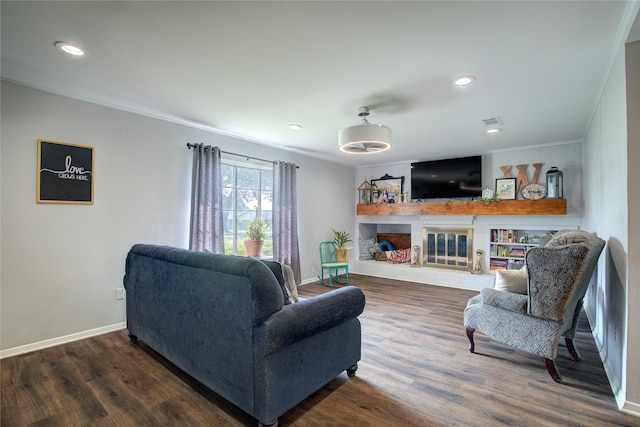 living room featuring dark wood-type flooring, a brick fireplace, and ornamental molding