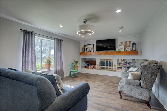 living room featuring a brick fireplace, crown molding, and hardwood / wood-style floors