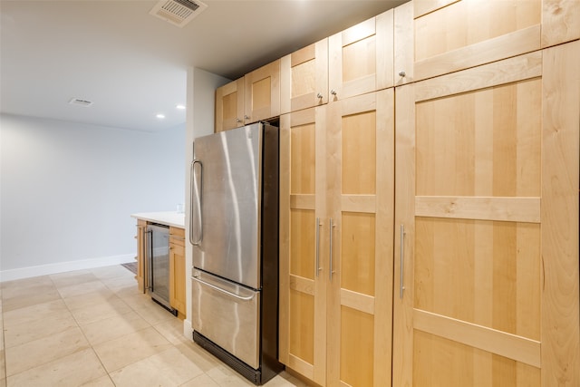 kitchen with light brown cabinets, wine cooler, stainless steel refrigerator, and light tile patterned floors