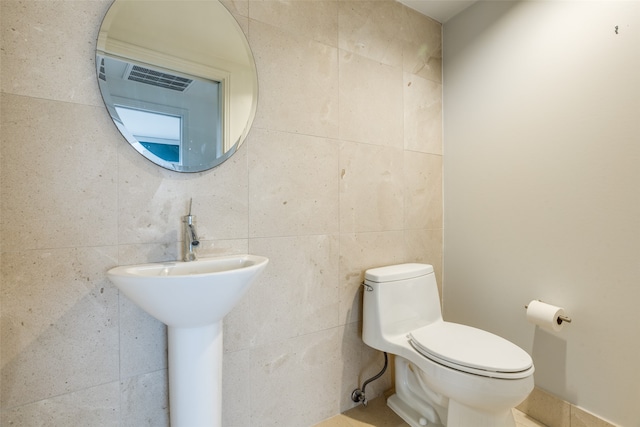 bathroom featuring toilet and tile walls