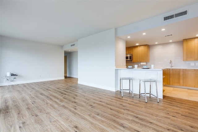 unfurnished living room with sink and light wood-type flooring