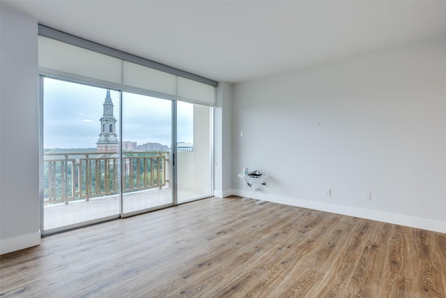 spare room with floor to ceiling windows and light hardwood / wood-style floors