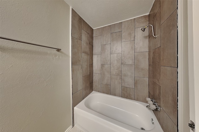 bathroom with tiled shower / bath combo and a textured ceiling