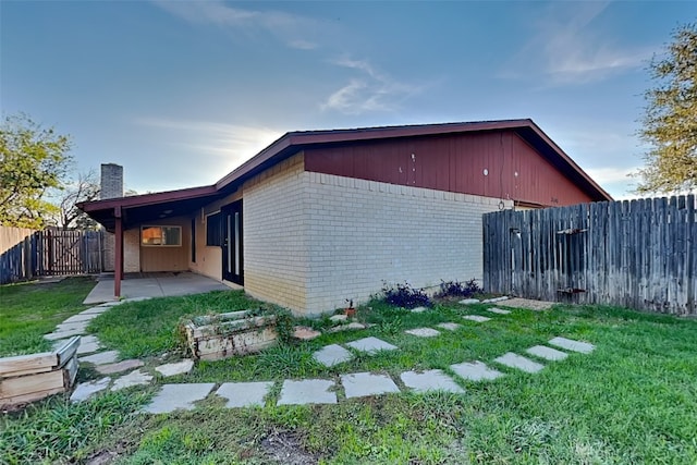 view of side of home featuring a patio area and a yard