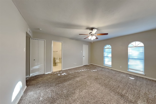 unfurnished bedroom featuring carpet, a textured ceiling, connected bathroom, and ceiling fan