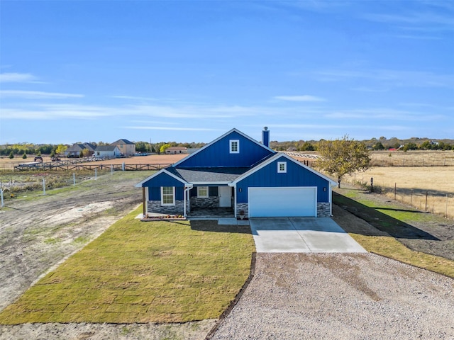 view of front of house featuring a rural view, a garage, and a front lawn