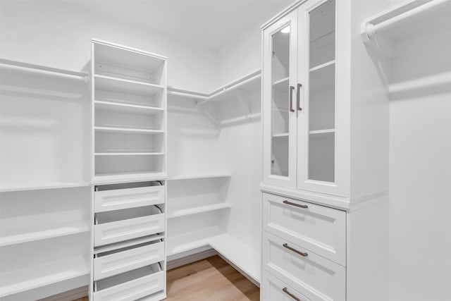 walk in closet with light hardwood / wood-style flooring