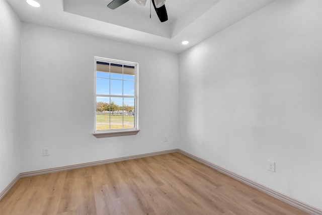 unfurnished room with a tray ceiling, light hardwood / wood-style flooring, and ceiling fan