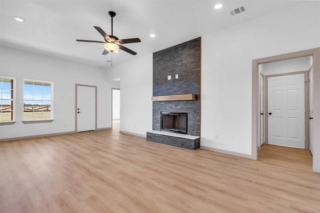 unfurnished living room with a stone fireplace, light hardwood / wood-style floors, and ceiling fan