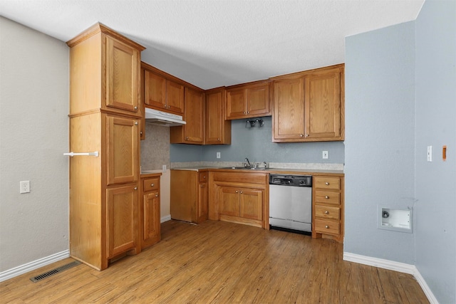 kitchen with dishwasher, light hardwood / wood-style floors, a textured ceiling, and sink