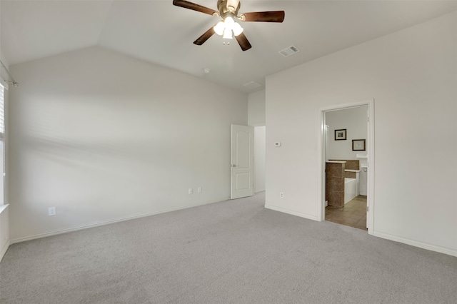 unfurnished bedroom featuring light carpet, vaulted ceiling, ensuite bath, and ceiling fan