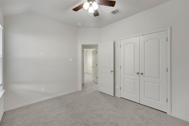 unfurnished bedroom featuring ceiling fan, a closet, light colored carpet, and lofted ceiling