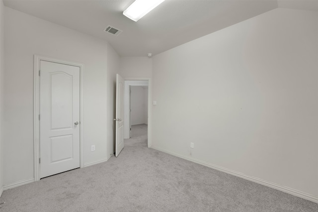 unfurnished bedroom featuring light carpet and vaulted ceiling