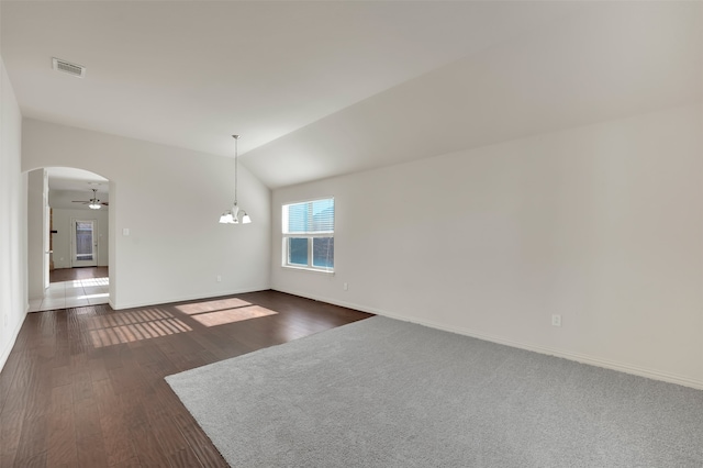 spare room with ceiling fan with notable chandelier, dark wood-type flooring, and vaulted ceiling