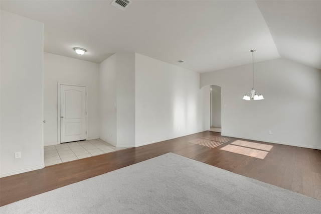 spare room with light hardwood / wood-style flooring, a chandelier, and lofted ceiling