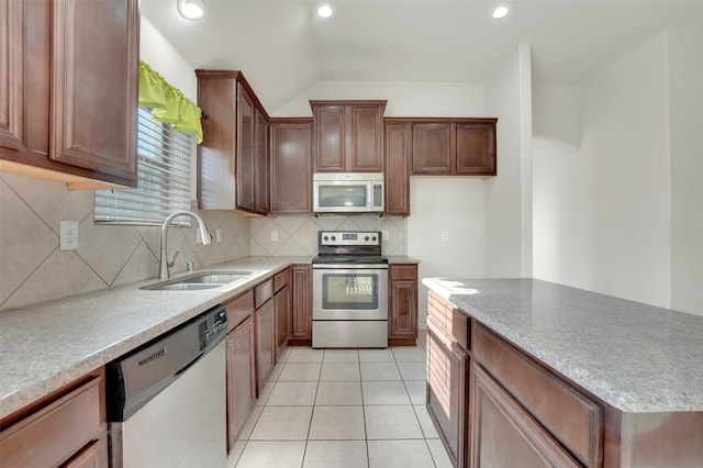 kitchen with decorative backsplash, appliances with stainless steel finishes, vaulted ceiling, sink, and light tile patterned floors