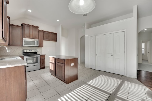 kitchen with sink, light tile patterned floors, tasteful backsplash, a kitchen island, and stainless steel appliances