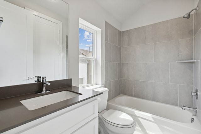 full bathroom featuring vanity, toilet, tiled shower / bath combo, and vaulted ceiling