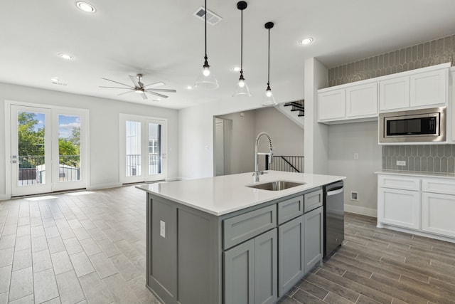 kitchen with pendant lighting, sink, ceiling fan, an island with sink, and appliances with stainless steel finishes