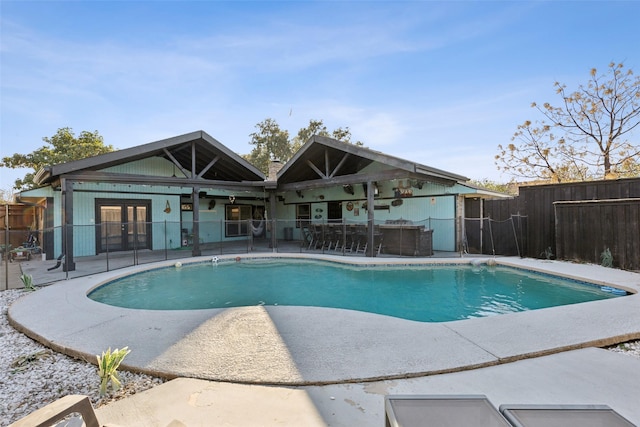 view of swimming pool featuring a bar, a patio, and french doors