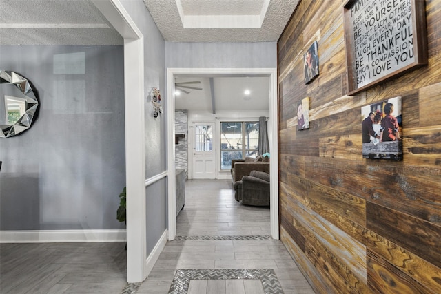 hallway with wood walls, wood-type flooring, and a textured ceiling