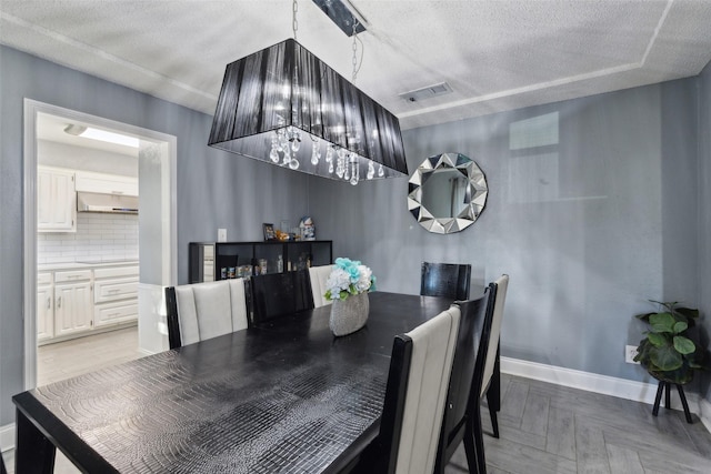 dining space with light parquet floors and a textured ceiling