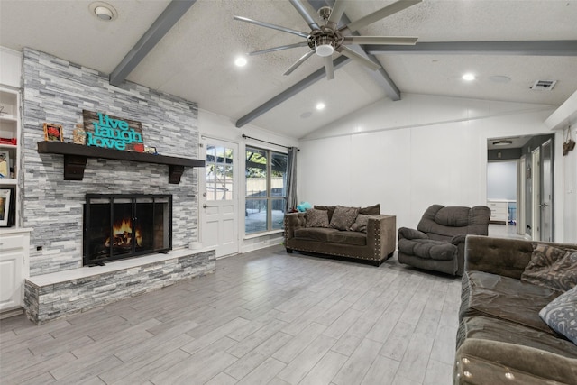 living room with lofted ceiling with beams, a stone fireplace, light hardwood / wood-style flooring, ceiling fan, and a textured ceiling