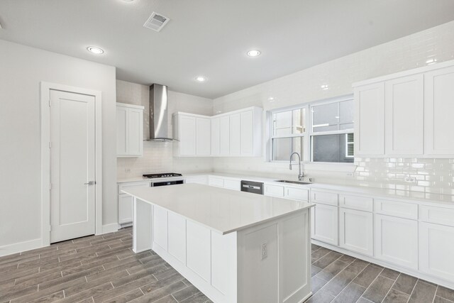 kitchen with hardwood / wood-style floors, a center island, white cabinets, sink, and wall chimney exhaust hood