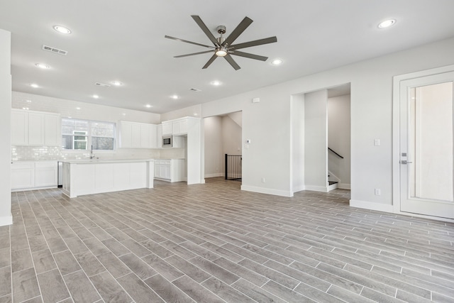 unfurnished living room with ceiling fan, sink, and light hardwood / wood-style flooring