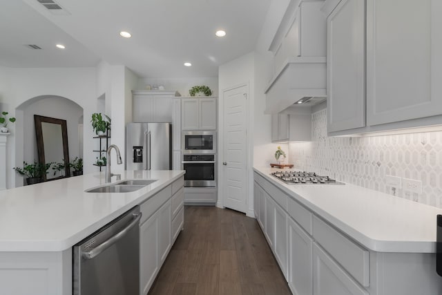 kitchen with white cabinetry, sink, stainless steel appliances, dark hardwood / wood-style floors, and an island with sink