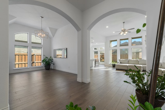 interior space with ceiling fan with notable chandelier, dark hardwood / wood-style flooring, and a high ceiling