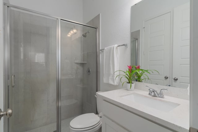 bathroom featuring vanity, a shower with shower door, and toilet