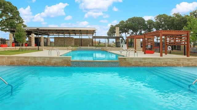 view of pool with pool water feature, a pergola, and a patio