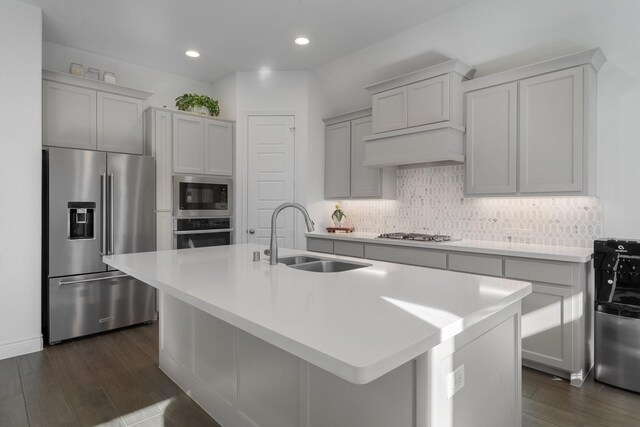 kitchen with appliances with stainless steel finishes, dark hardwood / wood-style flooring, a center island with sink, and sink