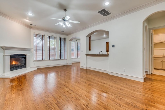 unfurnished living room featuring ornamental molding, ceiling fan, and light hardwood / wood-style flooring