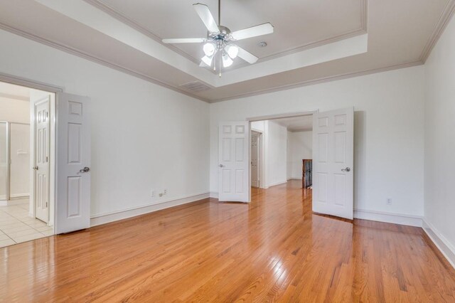 empty room featuring ceiling fan, vaulted ceiling, ornamental molding, and light hardwood / wood-style flooring