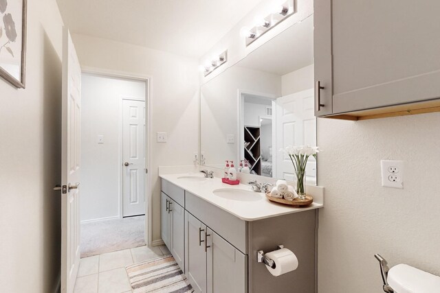 bathroom with double vanity, tile patterned flooring, a sink, and toilet