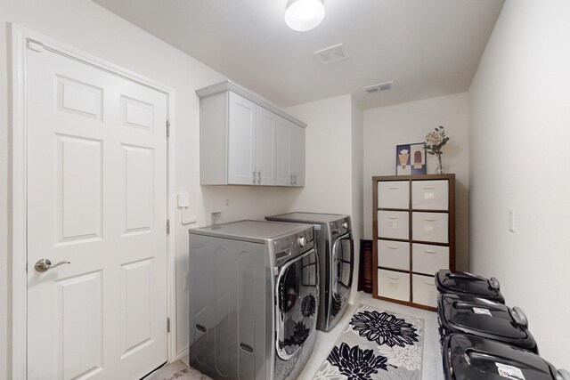 washroom featuring visible vents, cabinet space, and separate washer and dryer