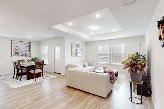 living area with light wood-type flooring, a tray ceiling, visible vents, and recessed lighting