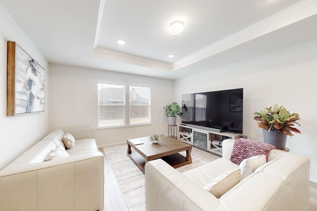 living area with light wood-style floors, recessed lighting, a raised ceiling, and crown molding