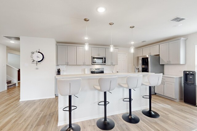 kitchen with appliances with stainless steel finishes, pendant lighting, light countertops, and visible vents