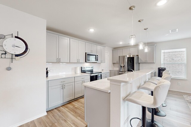 kitchen with visible vents, a kitchen breakfast bar, a center island, hanging light fixtures, and stainless steel appliances